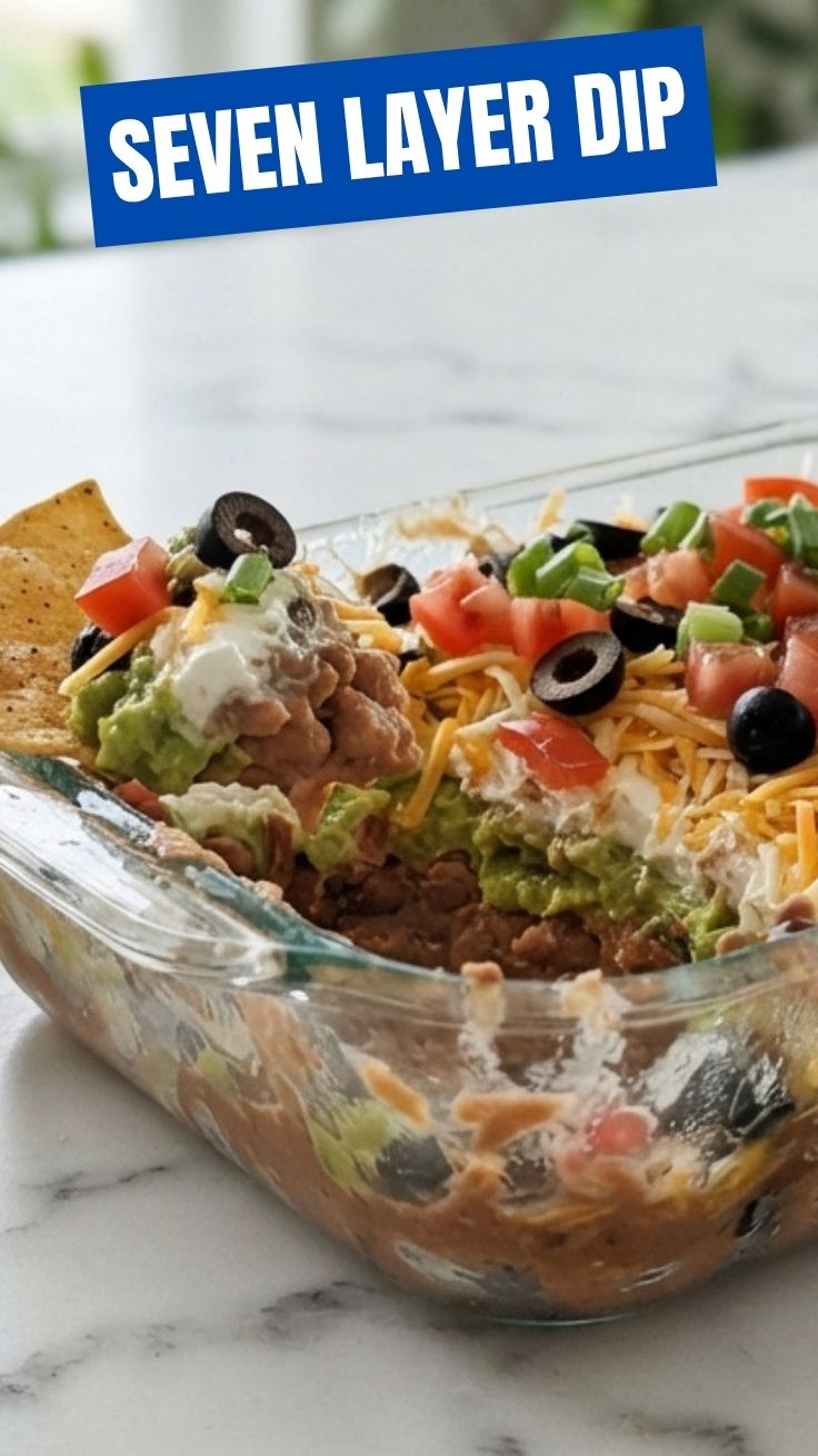 A fresh seven layer dip with distinct colorful layers in a clear bowl